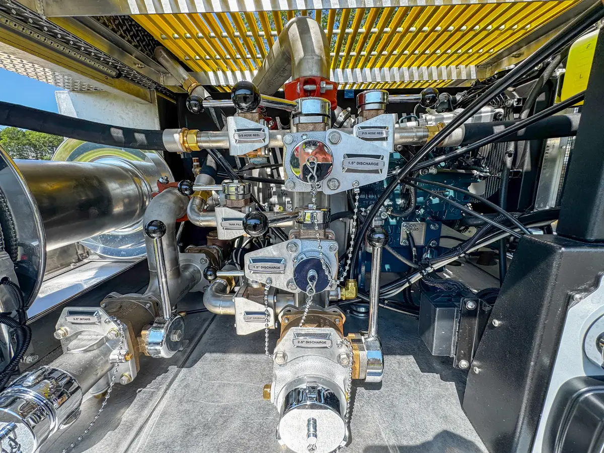 Rear pump plumbing close-up with intake fittings and valve handles.